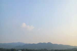 Sawah hijau di Desa Pematang dengan gubuk petani dan pegunungan di latar belakang, lokasi sengketa Batu Batas 100 tahun