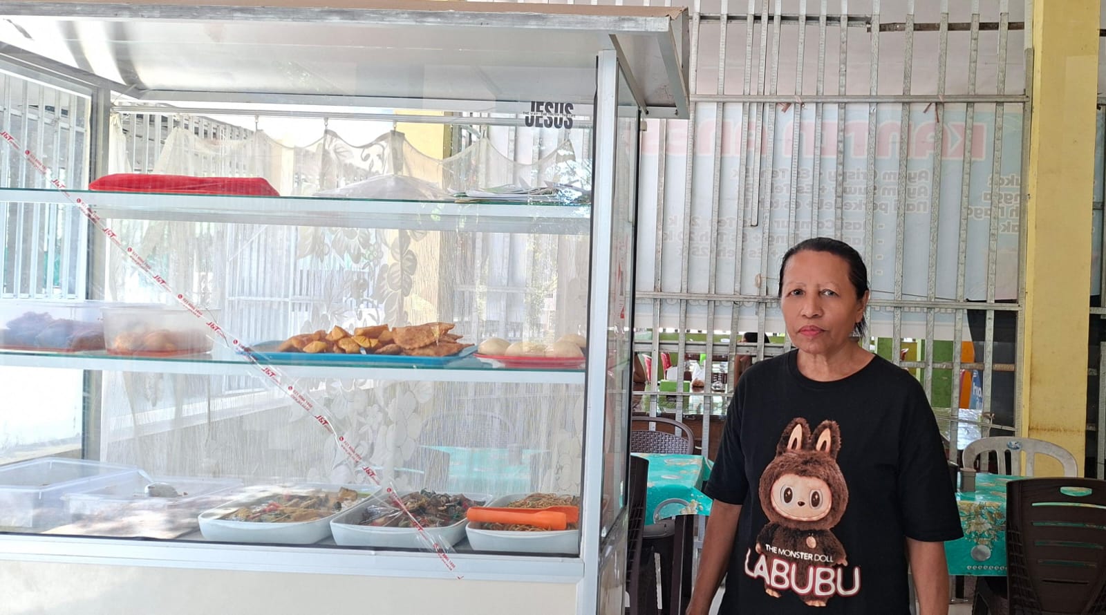 Hana Agsamina Patttypelohi pemilik usaha kantin di Kupang berdiri di depan etalase makanan dengan dukungan KUR BRI